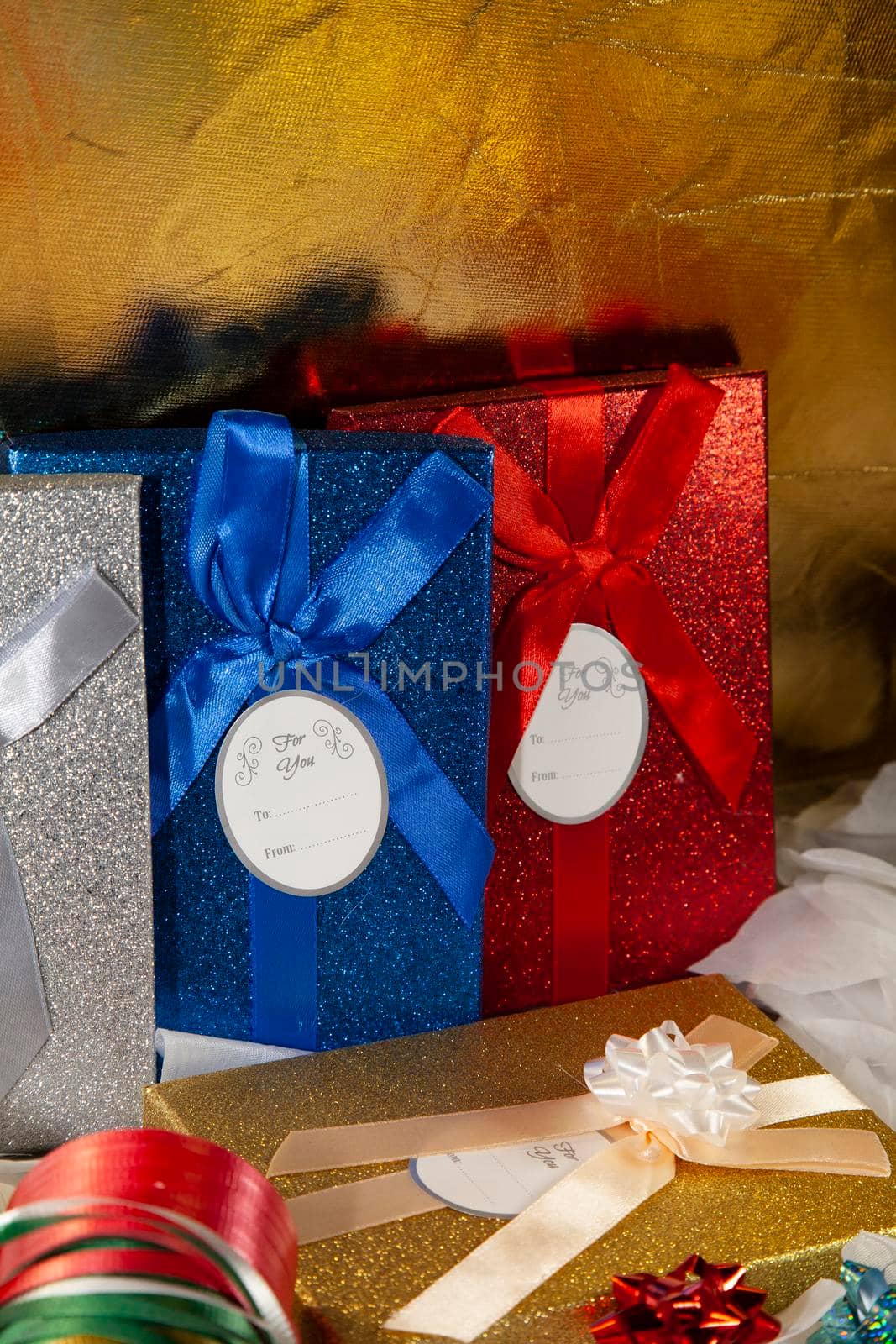 Silver, blue, red, and gold gift boxes near multicolored wrapping ribbon