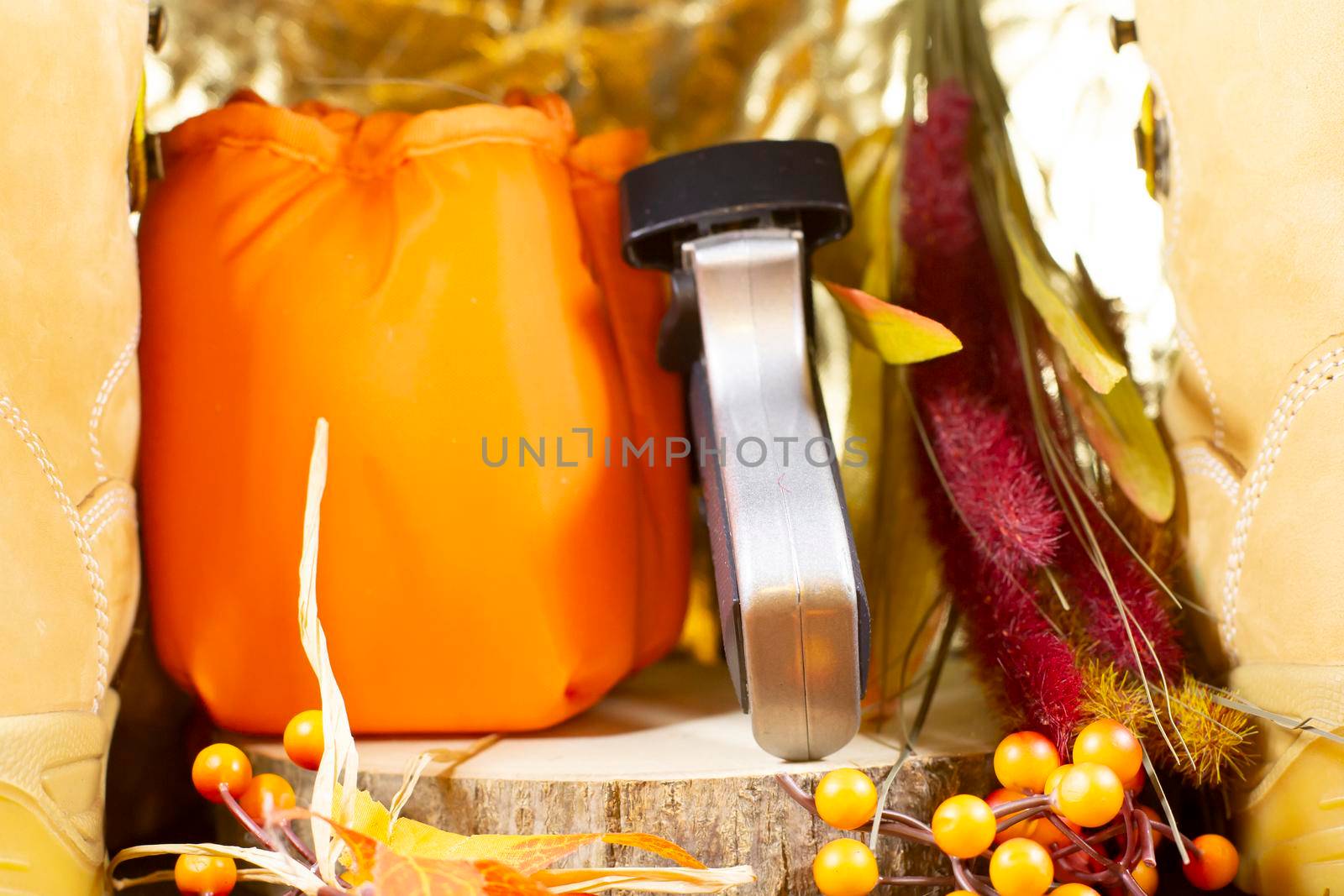 BB pistol and hunter orange carrying pouch on a slab of wood between two boots 