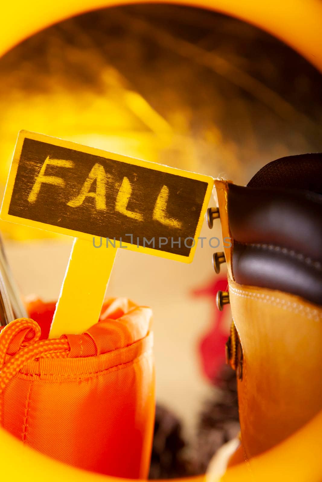 "FALL" sign in a hunter orange carrying pouch next to a boot, with a golden tone