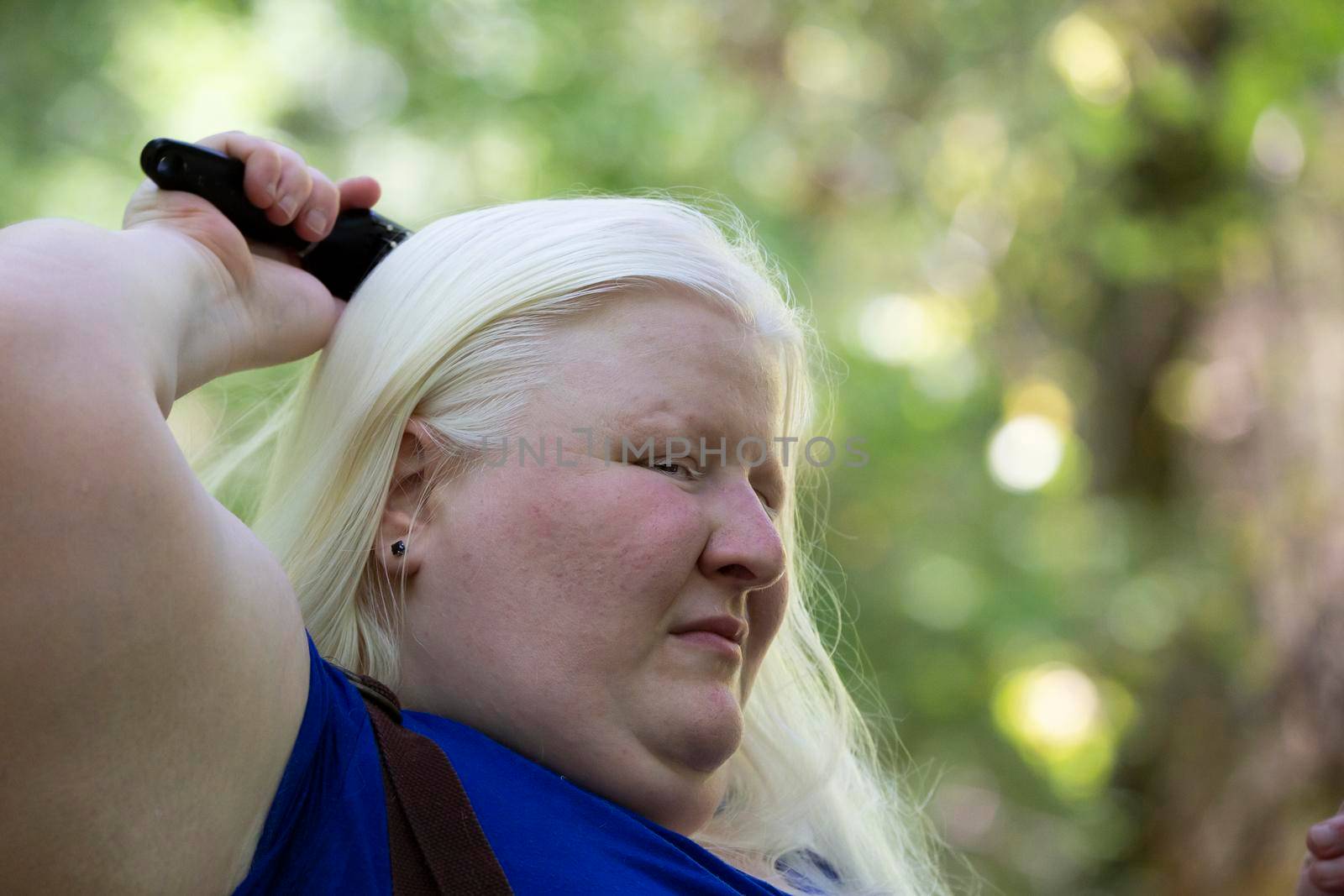 Close up of an albino woman brushing her hair in nature