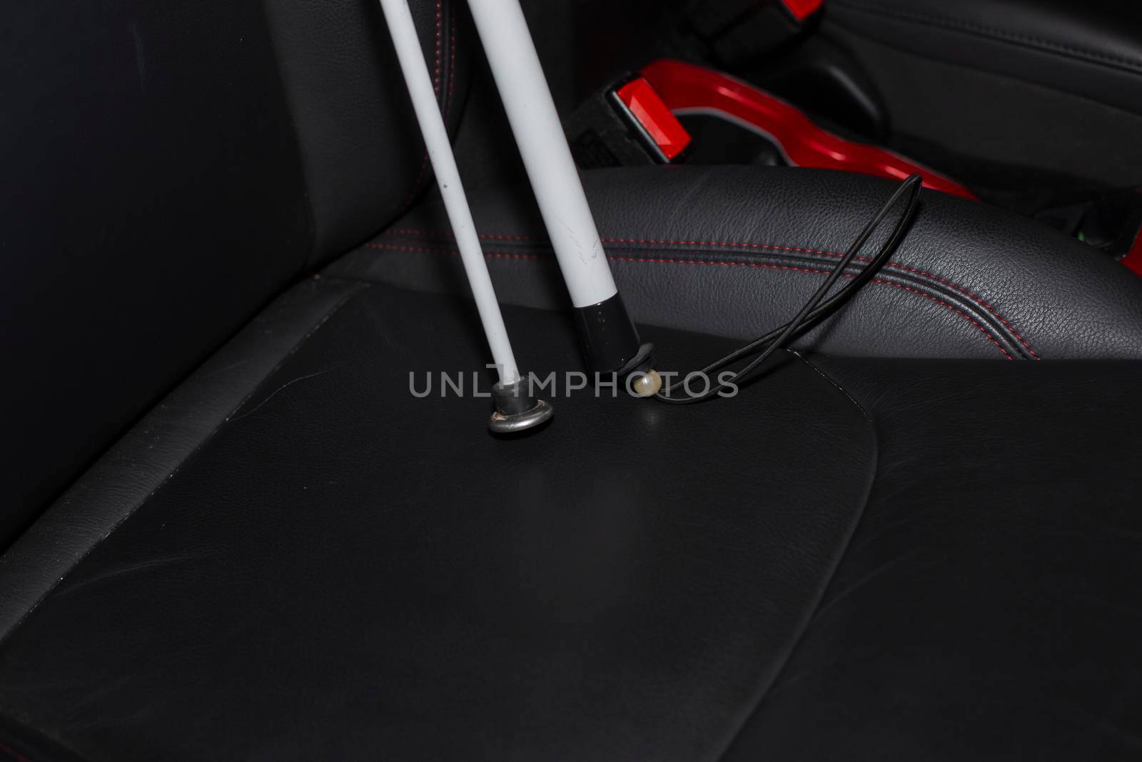 Folded white cane in the passenger seat of a vehicle