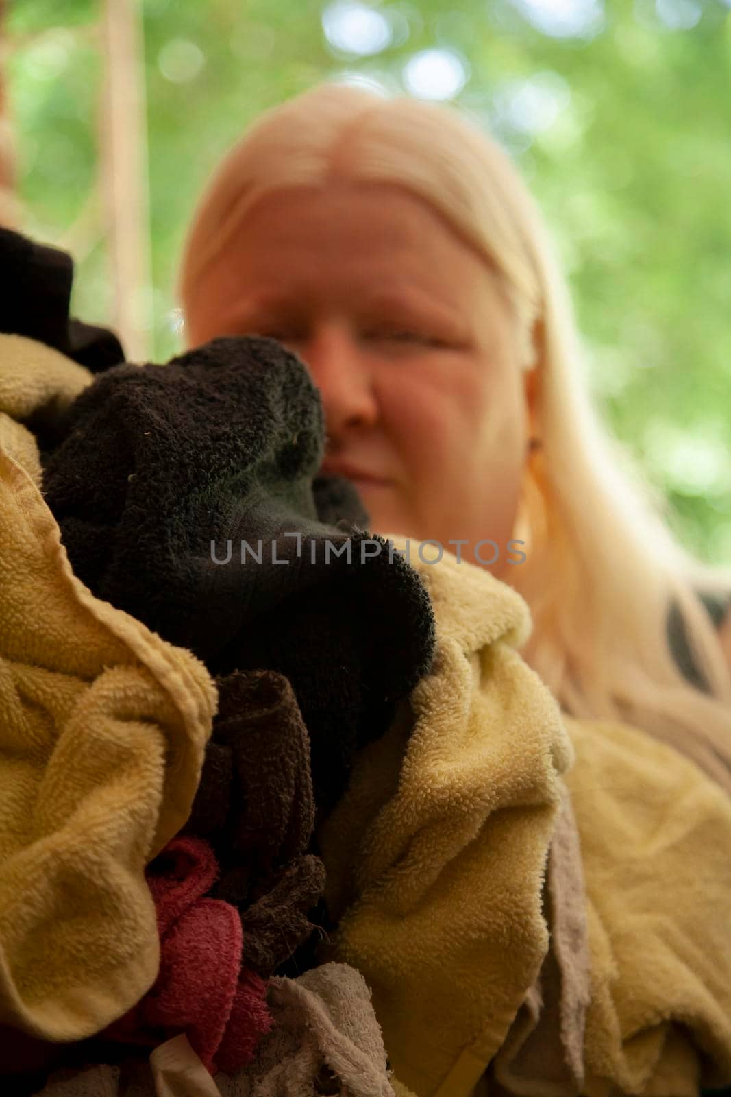 Woman carrying dirty yellow and black towels with other colorful wash cloths to do laundry