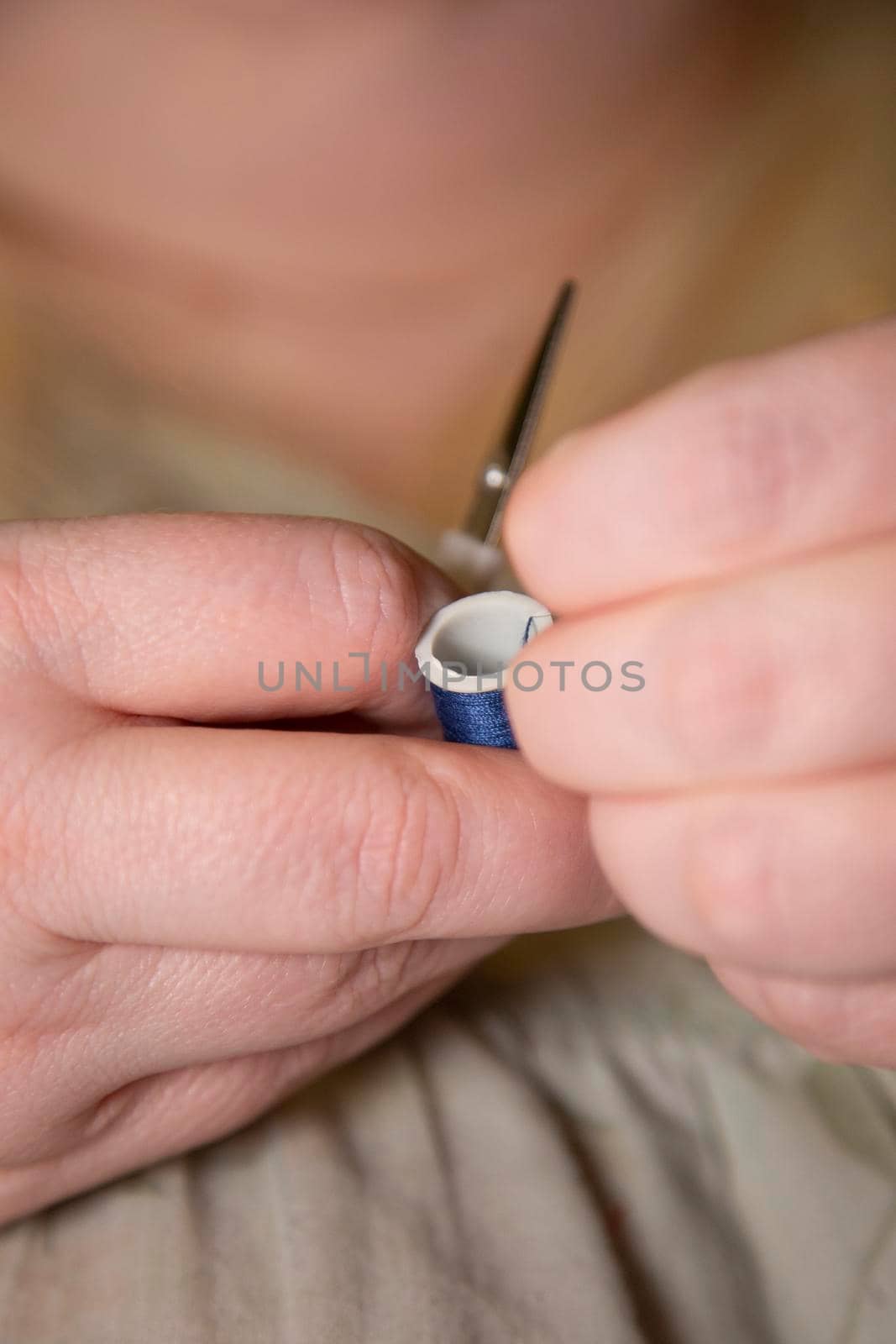 Woman pulling blue thread, preparing to cut it