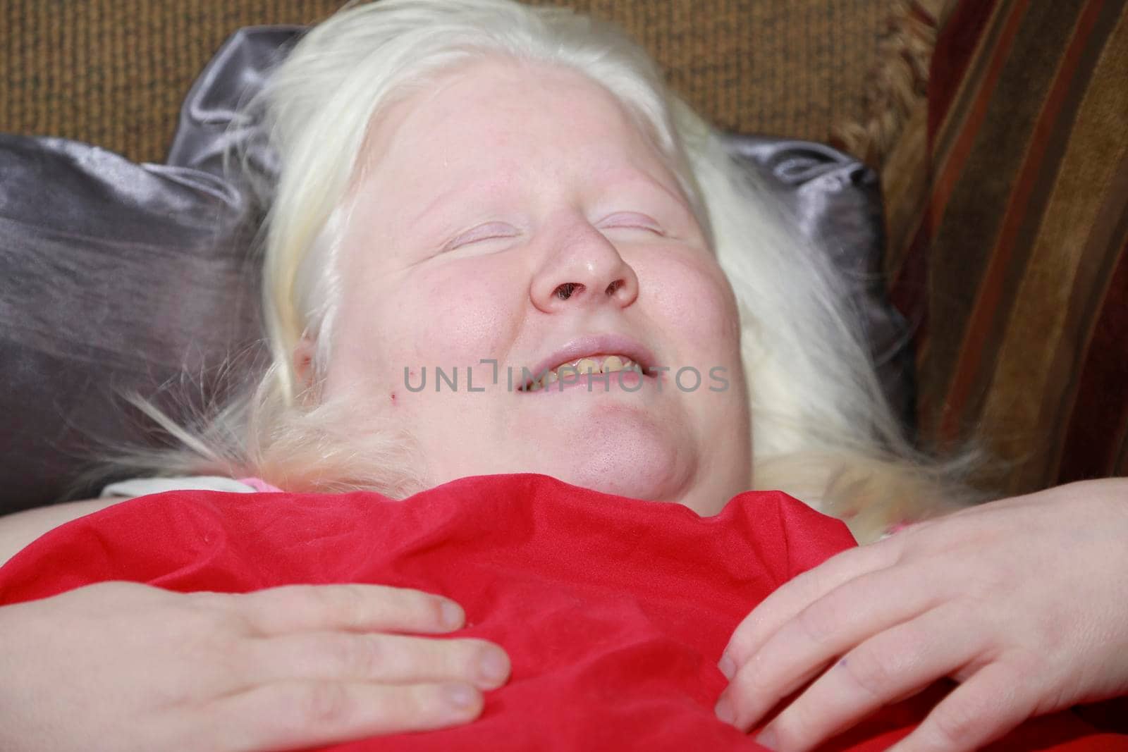 Woman resting under a red sheet on a couch