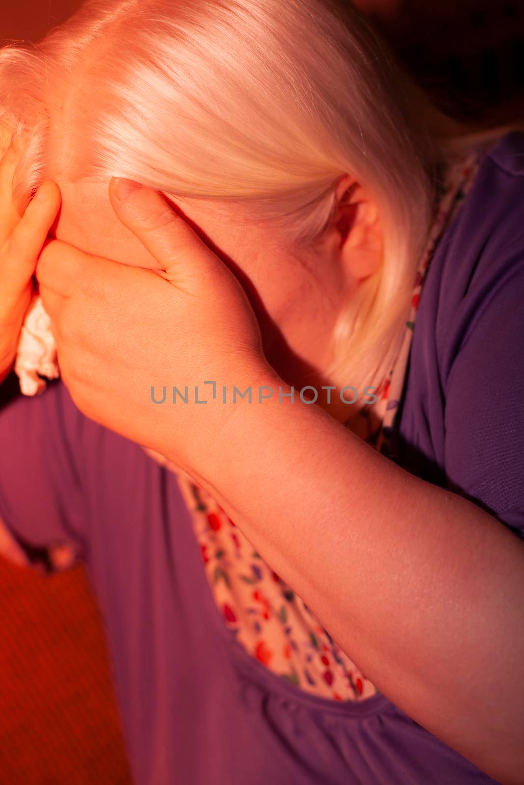 Upset woman with her hand over her eyes in a red tint