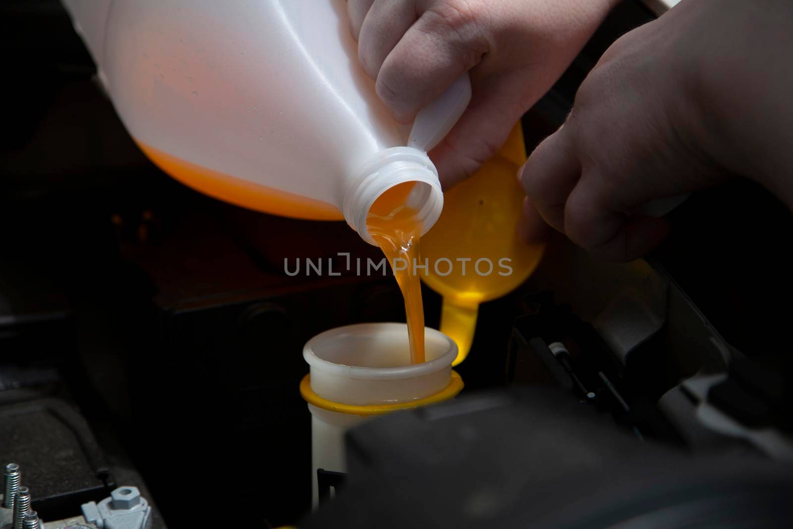Windshield washer fluid being poured into the container in an automobile