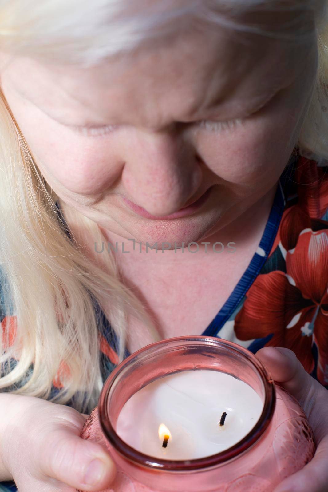 Albino woman enjoying the scent of a lit peach-colored candle