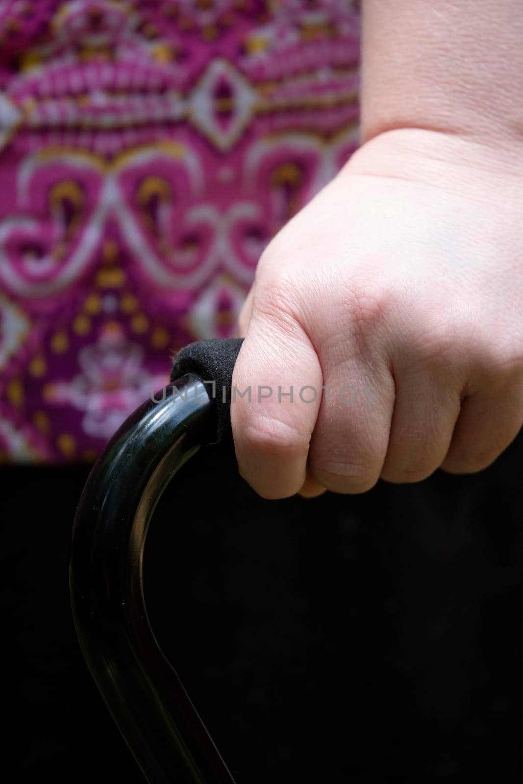 Close up of a woman's hand wrapped around a black cane