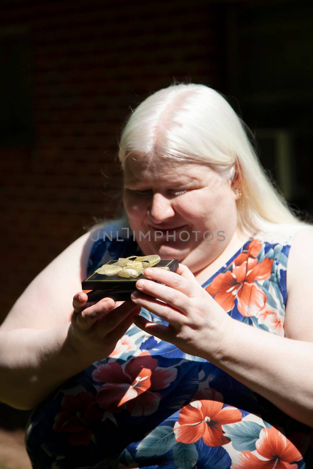 Albino woman opening a black gift box with a gift card in it
