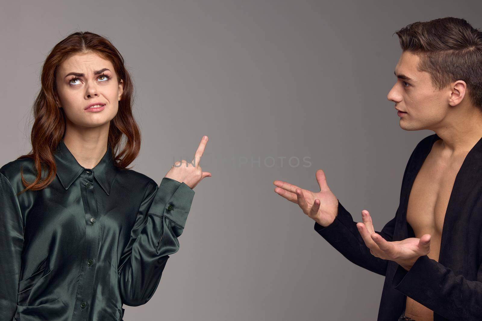 A woman shows her thumb up and a puzzled man gestures with his hands on a gray background. High quality photo