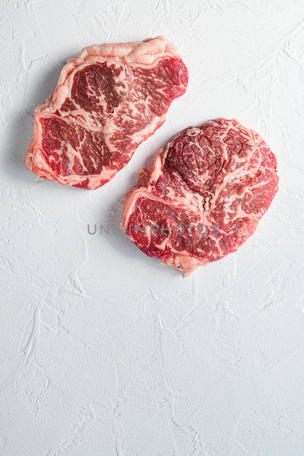Beef top blade steak, organic meat. White textured background. Top view with space for text