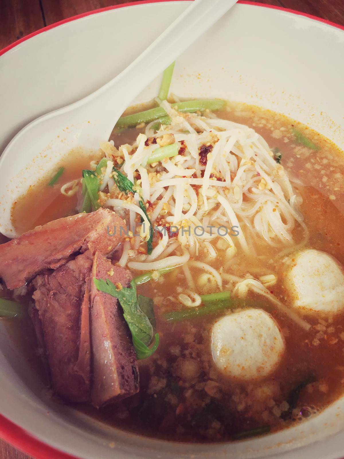 Delicious noodles with pork and pork balls with soup in white in Thai style food. Thai peoples call Boat Noodles, breakfast with bowl on wooden background meat. Noodle of traditional Thai food. by NarinNonthamand