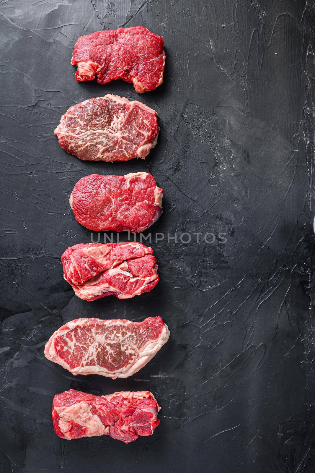 Raw set of rump, top blade, chuck roll beef steak cut, on black textured background, top view with space for text