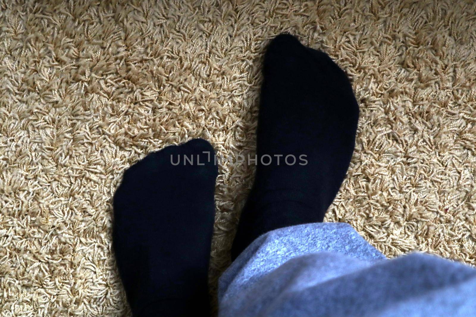 Men's legs in black socks on a background of fluffy yellow carpet