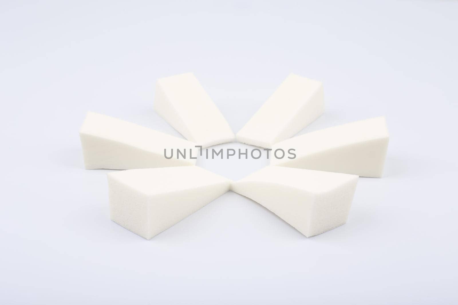 Triangle shaped make up sponges arranged in a circle on white background. Concept of visage and beauty blenders by Senorina_Irina