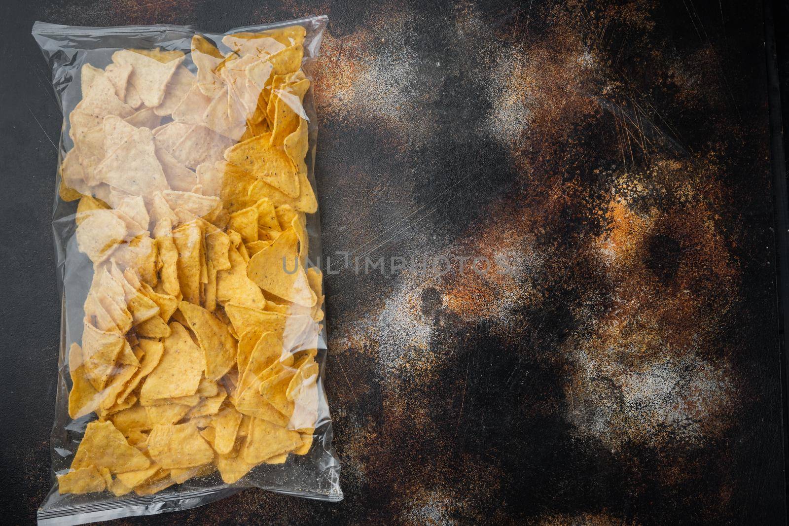 Nachos, corn tortilla in bag, on old dark rustic background, top view or flat lay with copy space for text