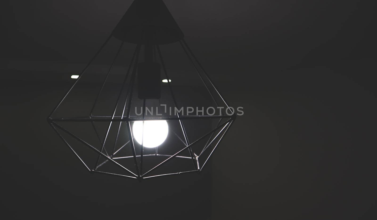Chandelier with black iron rods on the ceiling in a room with a light bulb