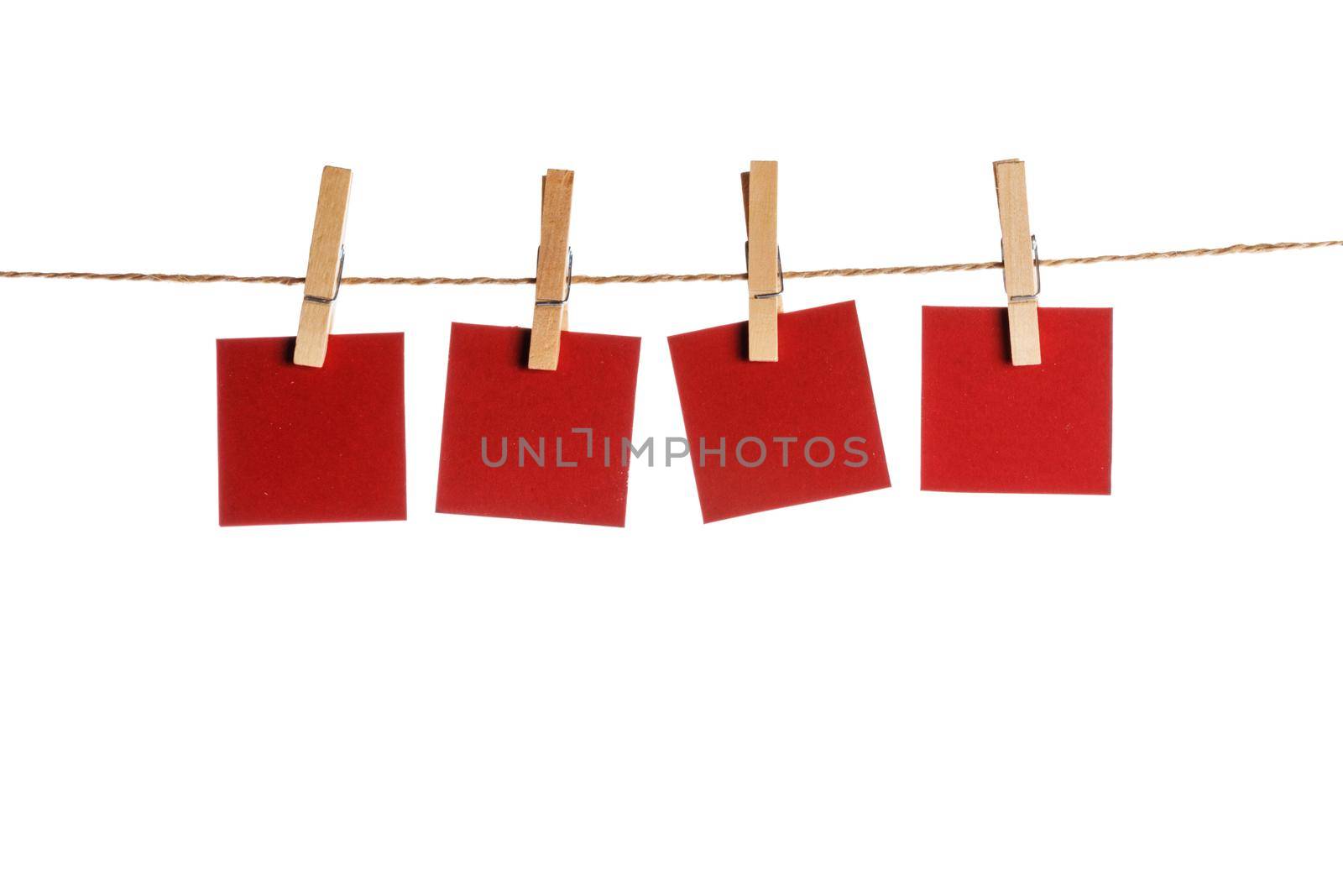 Set of four red blank paper notes held on a string with clothespins isolated on white background