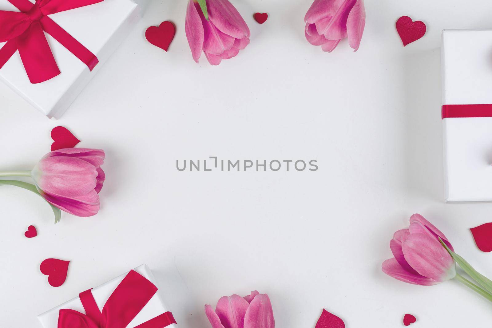 Pink tulip flowers gifts and red hearts composition on white background top view with copy space. Valentine's day, birthday, wedding, Mother's day concept. Copy space