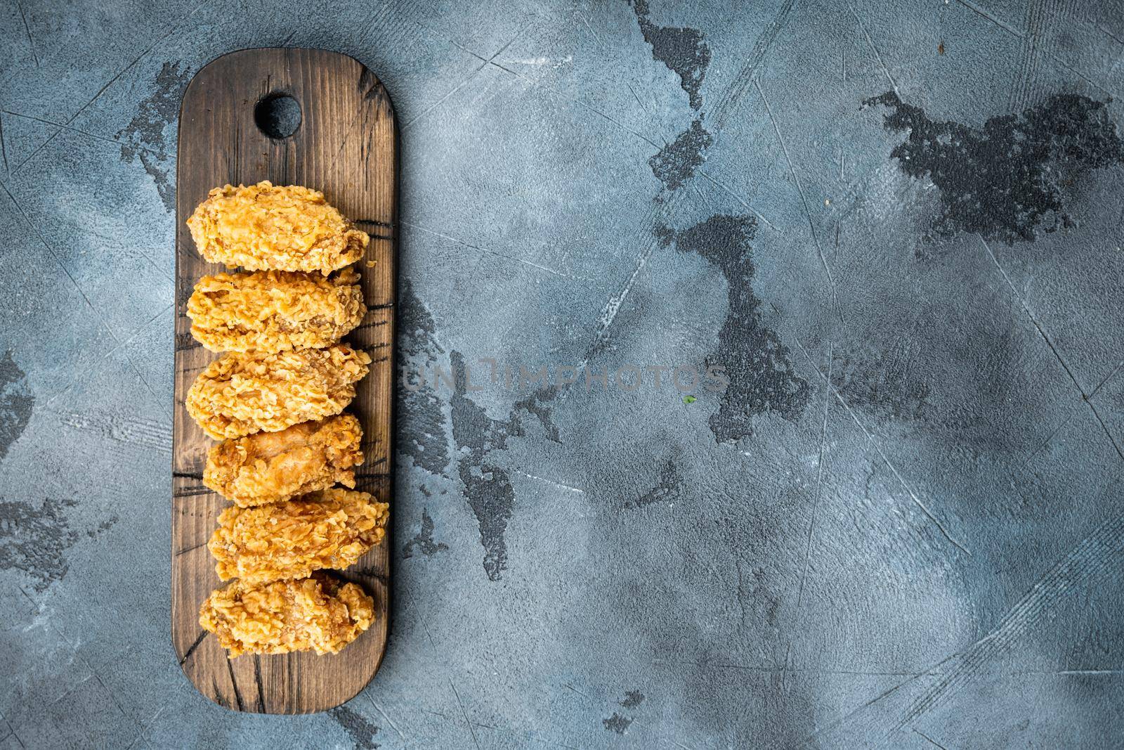Fried chicken wings parts on grey background, top view, with copy space.