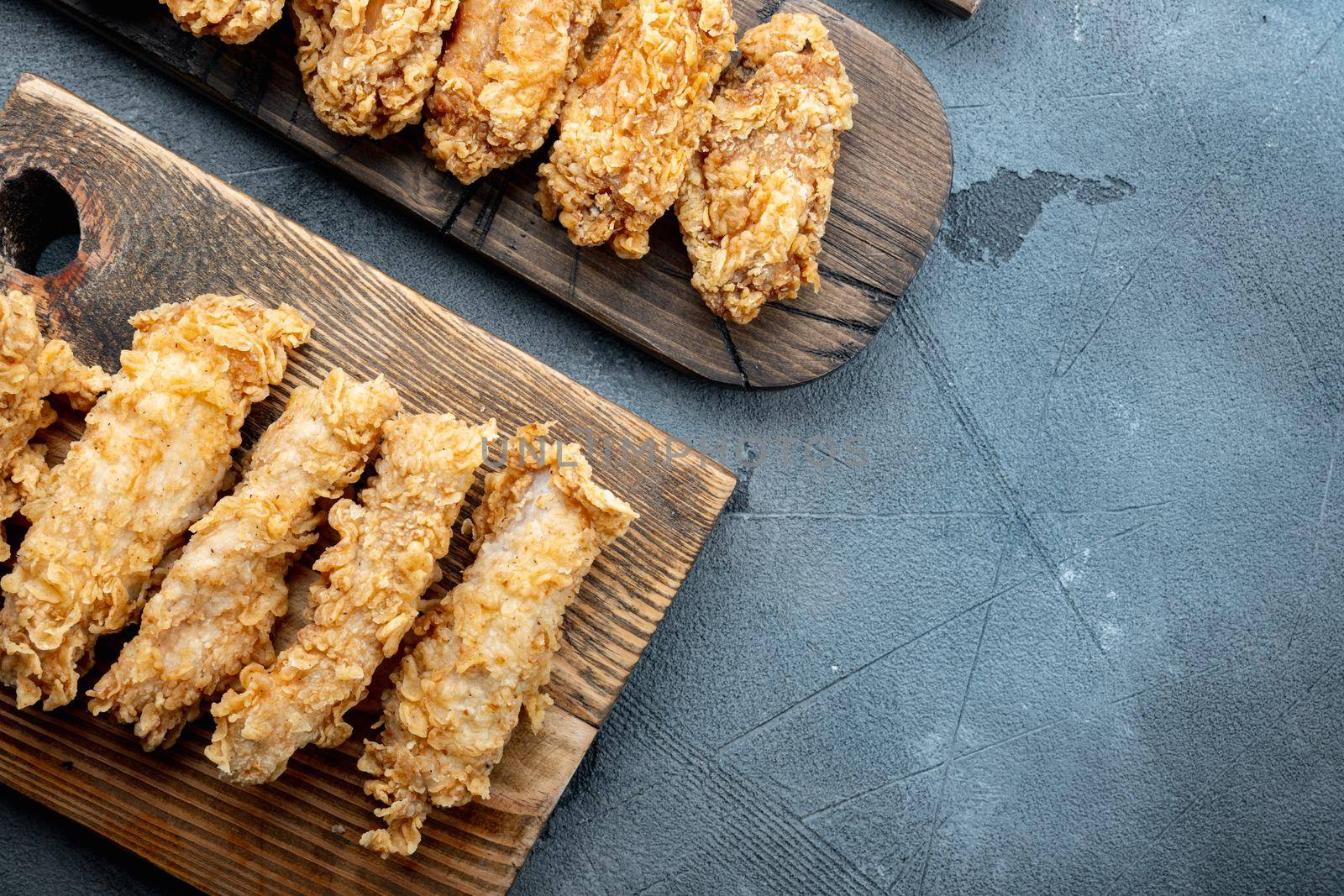 Crispy kentucky fried chicken cuts on grey background, top view, with space for text.