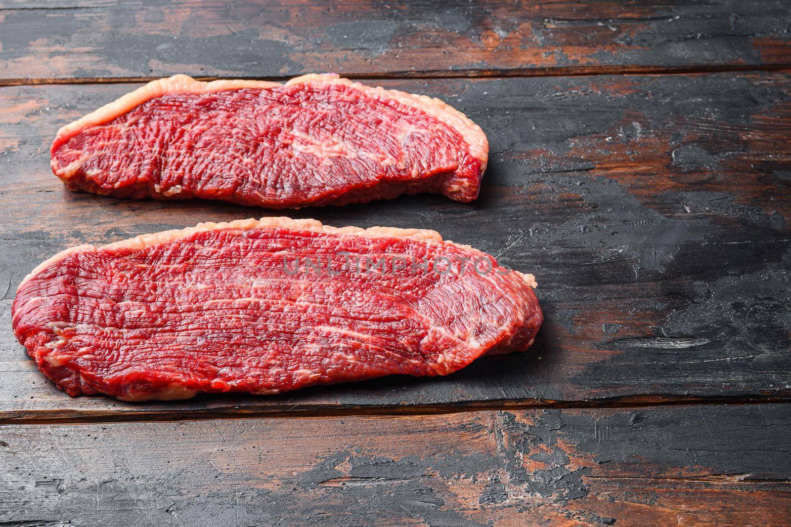 Organic picanha beef meat steaks, over dark old wooden background, side view space for text