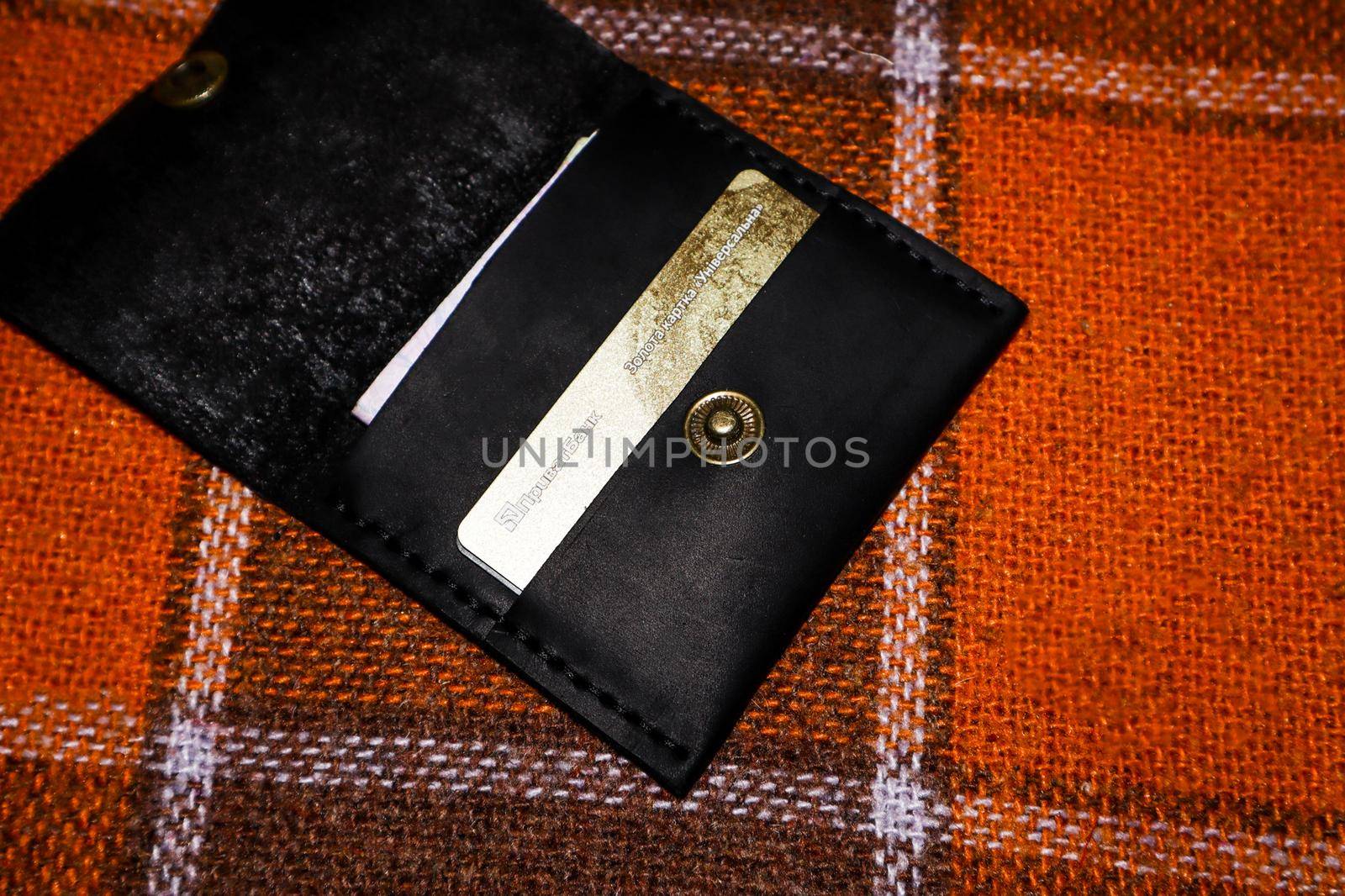 Leather wallet stitched with white threads with cards on a plaid in a cage