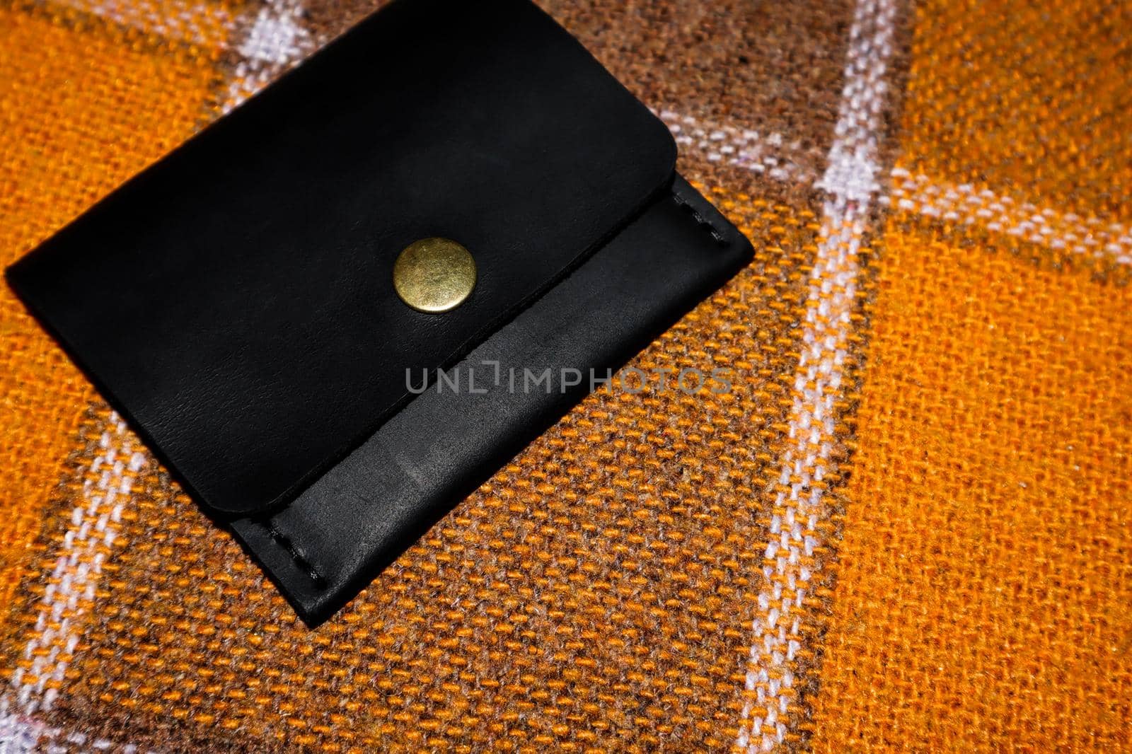 The leather wallet is sewn with white threads on an orange cover in a cell