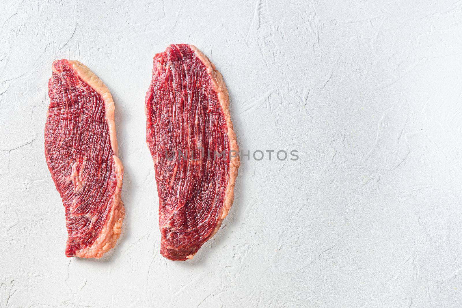 Organic picanha beef meat steaks, over white textured background, top view space for text