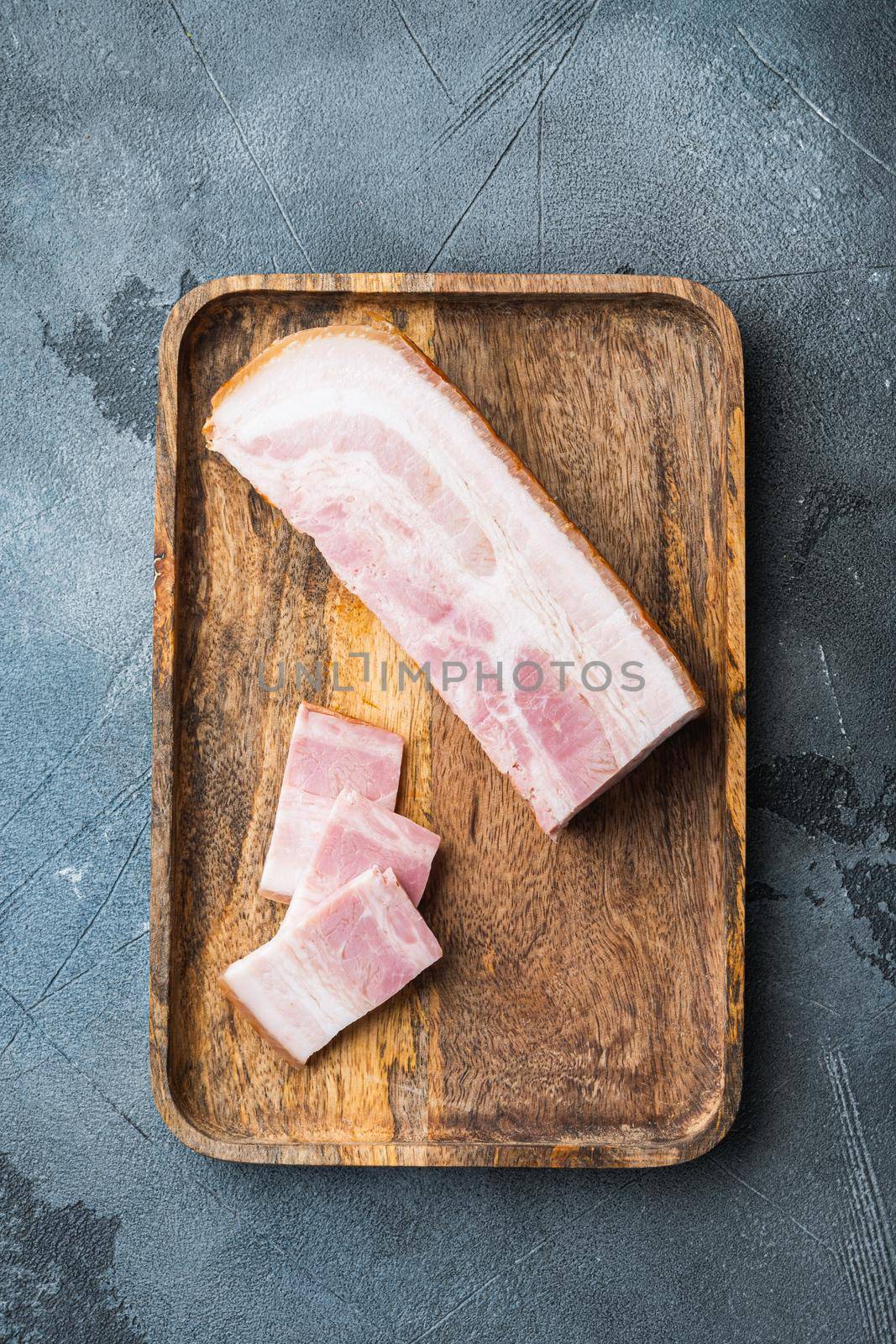 Bacon pancetta cut and sliced on grey textured background, top view.
