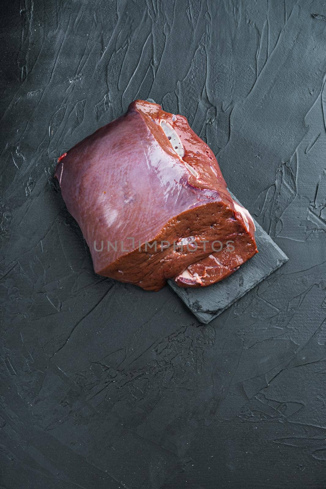 Beef liver on black background with copy space.