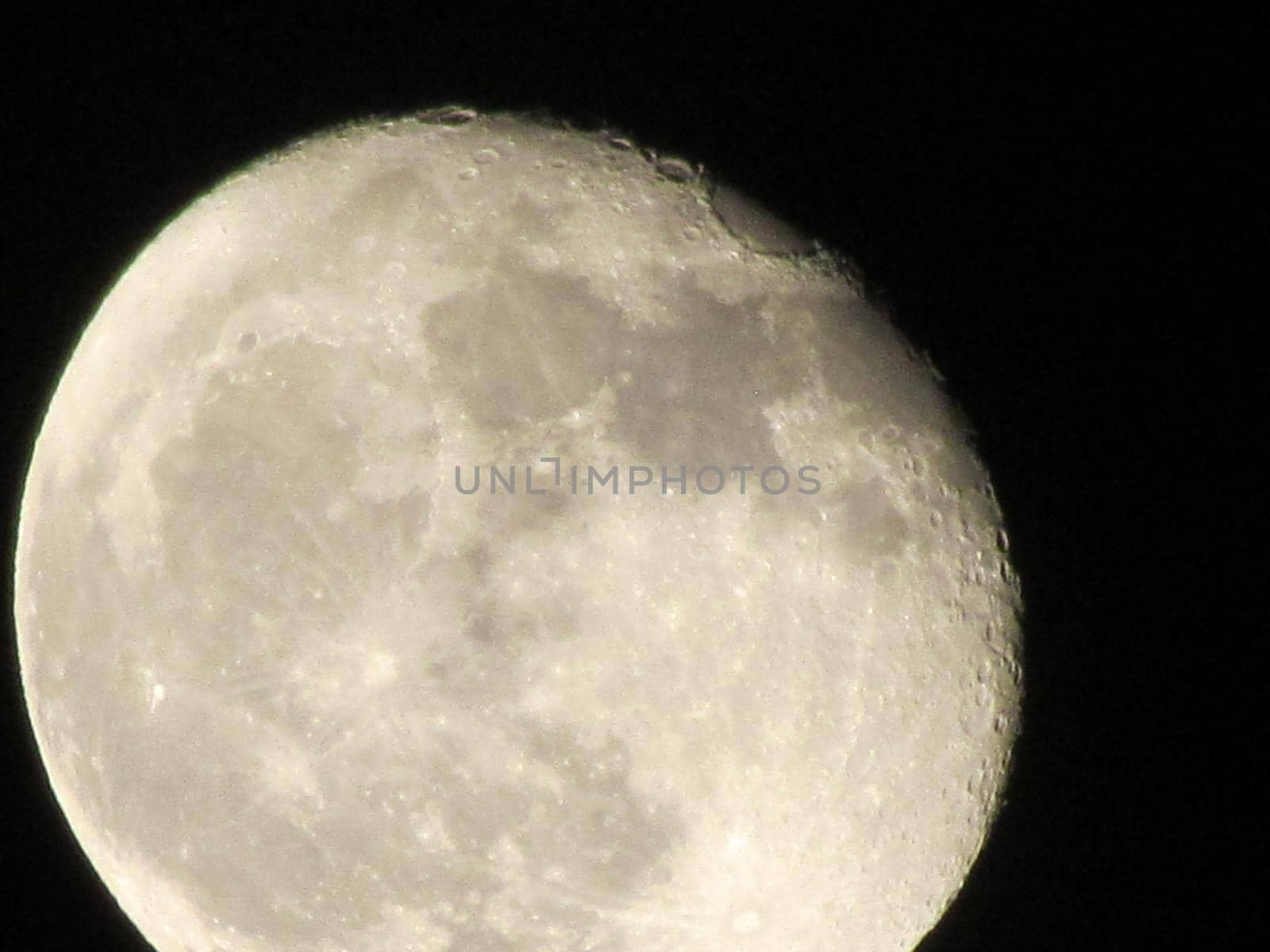 Earth's Moon Glowing On Black Background. The Moon close-up on a black night sky shot through a telephoto camera.