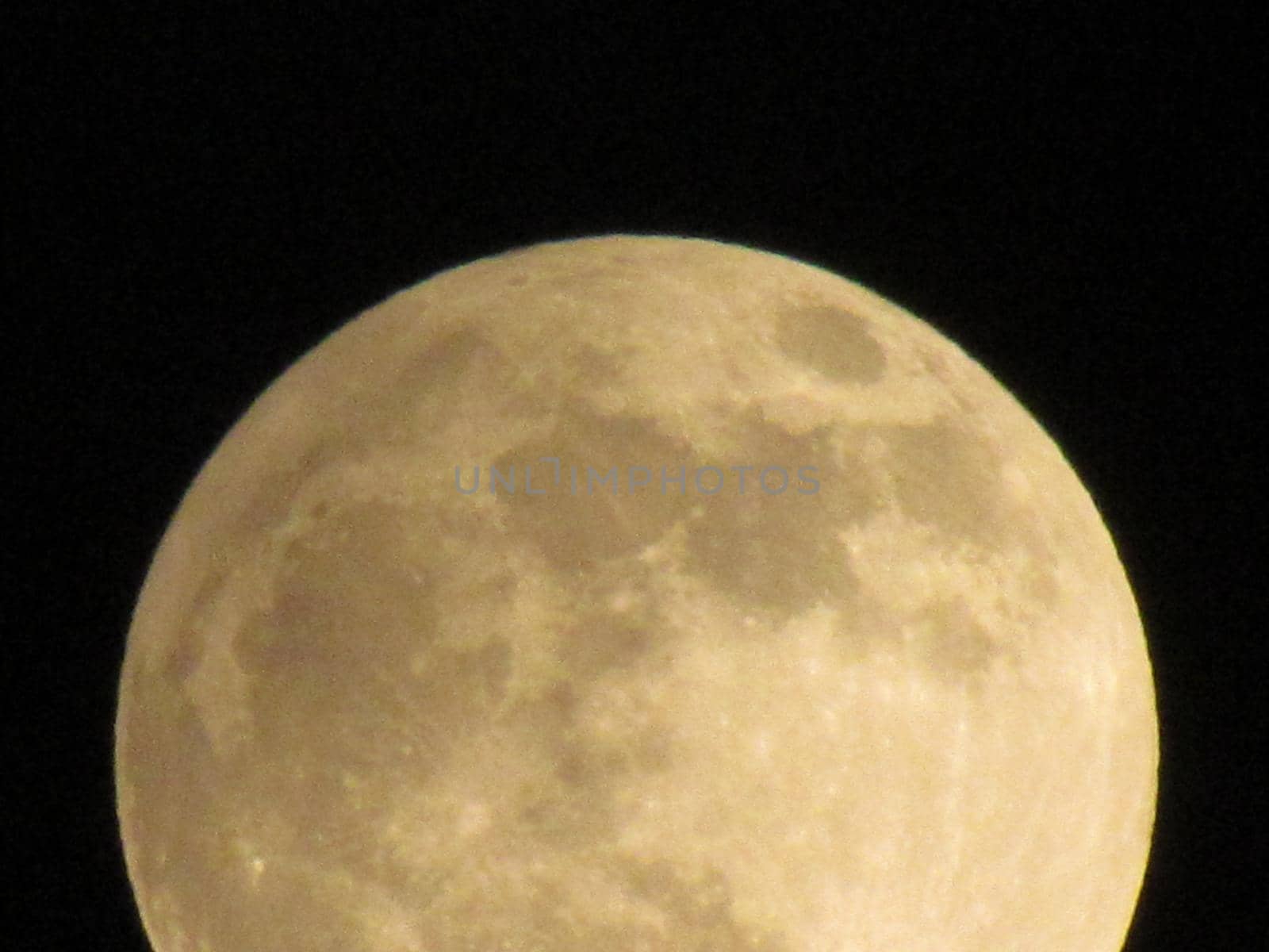 Earth's Moon Glowing On Black Background. The Moon close-up on a black night sky shot through a telephoto camera.