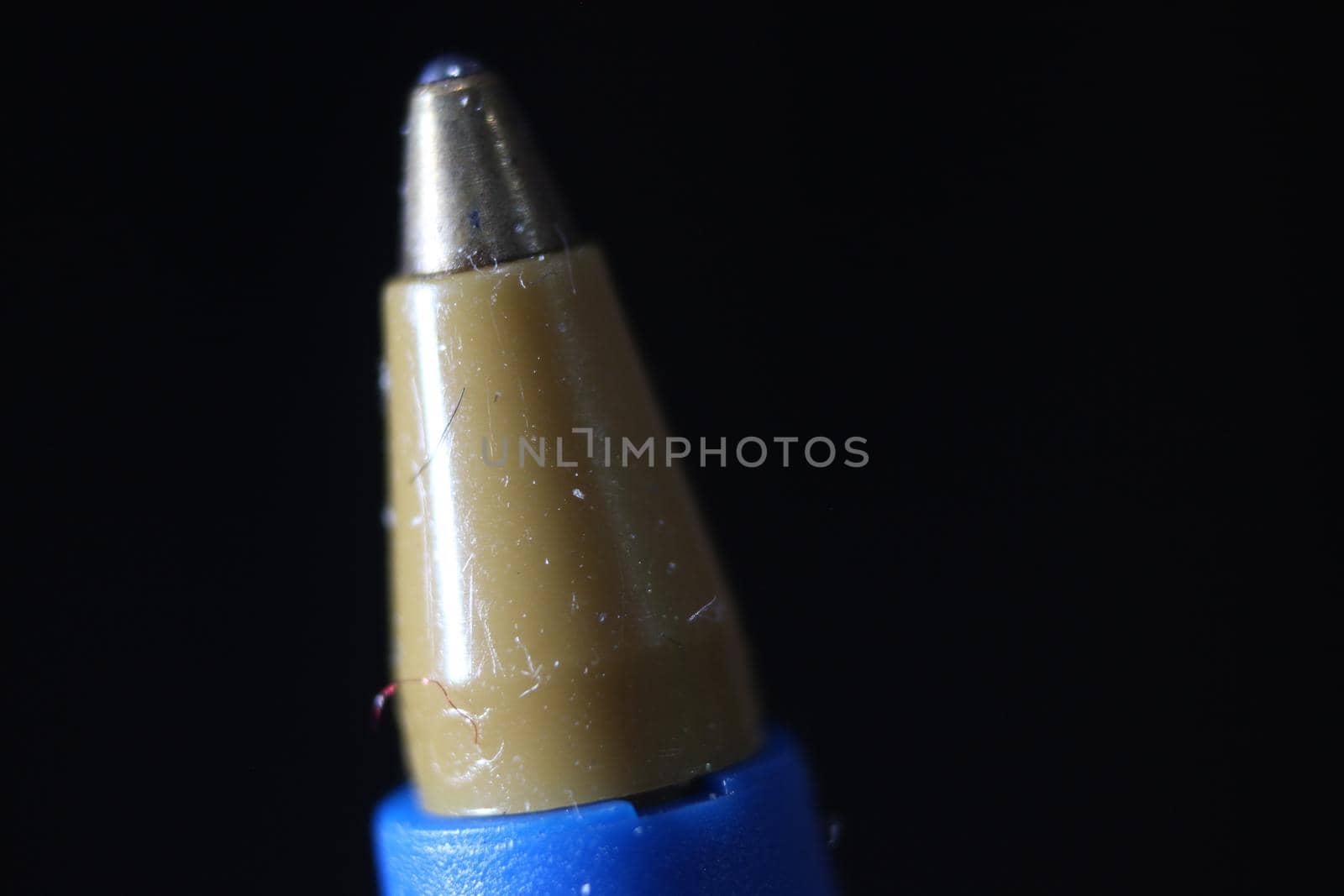 Macro photo of ballpoint pen tip with dark grey background. by Photochowk