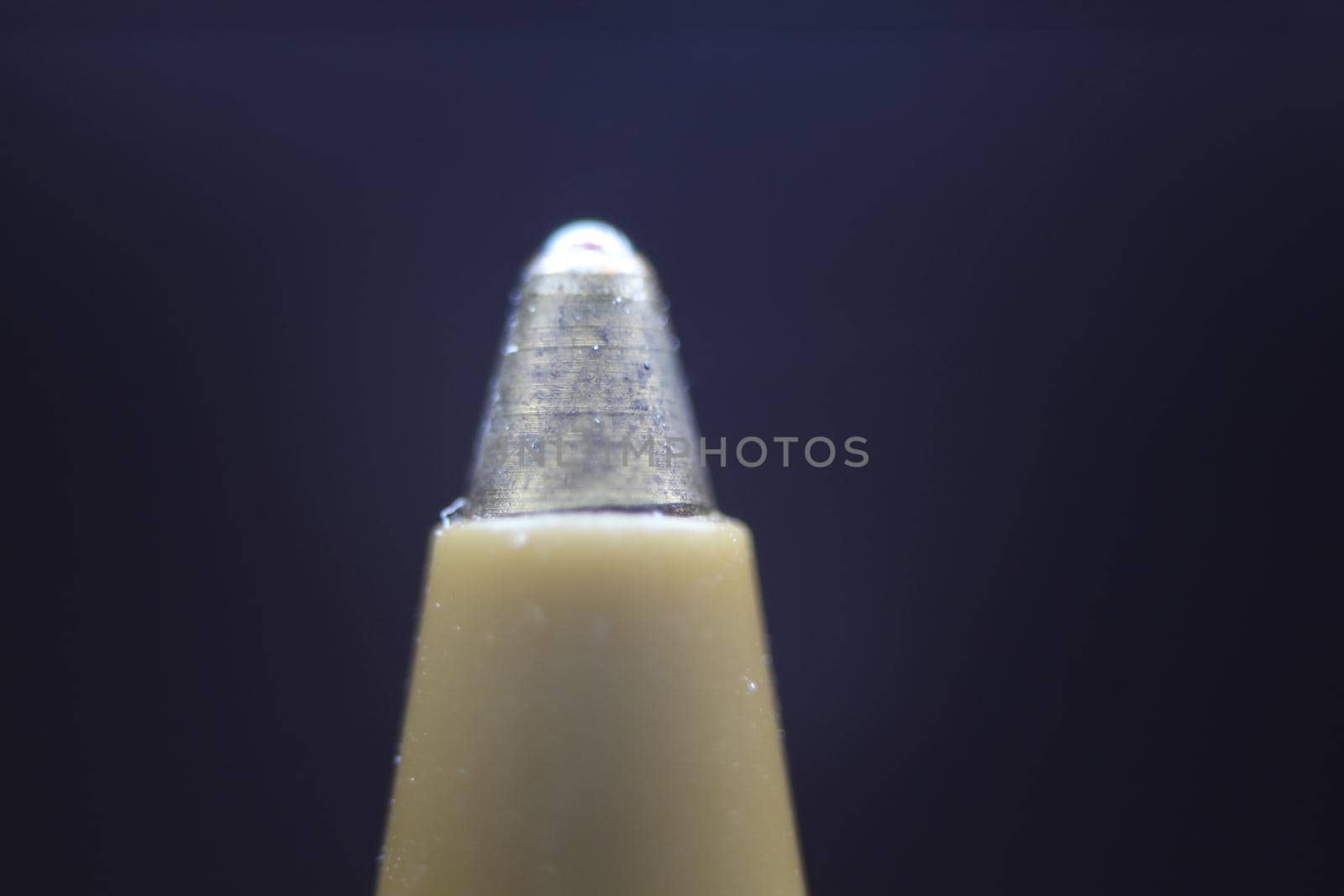 Macro photo of ballpoint pen tip with dark grey background. Extreme macro image of metal ballpoint pen on grey background.