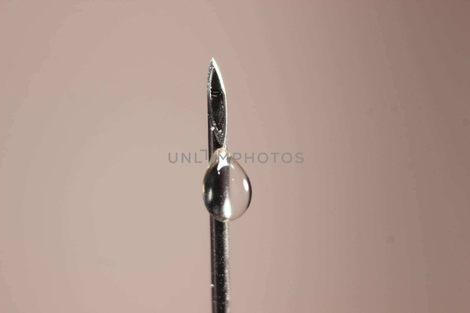 Close-up of vaccine drop on syringe needle. Water drop falling from the syringe needle