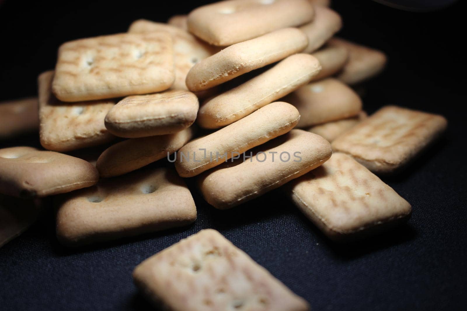 Close up top view of of biscuit cookies. Many rectangular biscuits with small pores on black floor