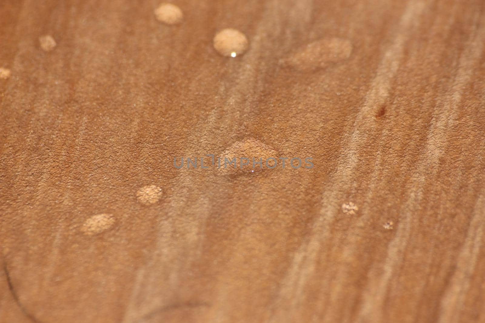 Closeup selective focus view of water drops on wooden floor. Abstract raindrops pattern on wooden board