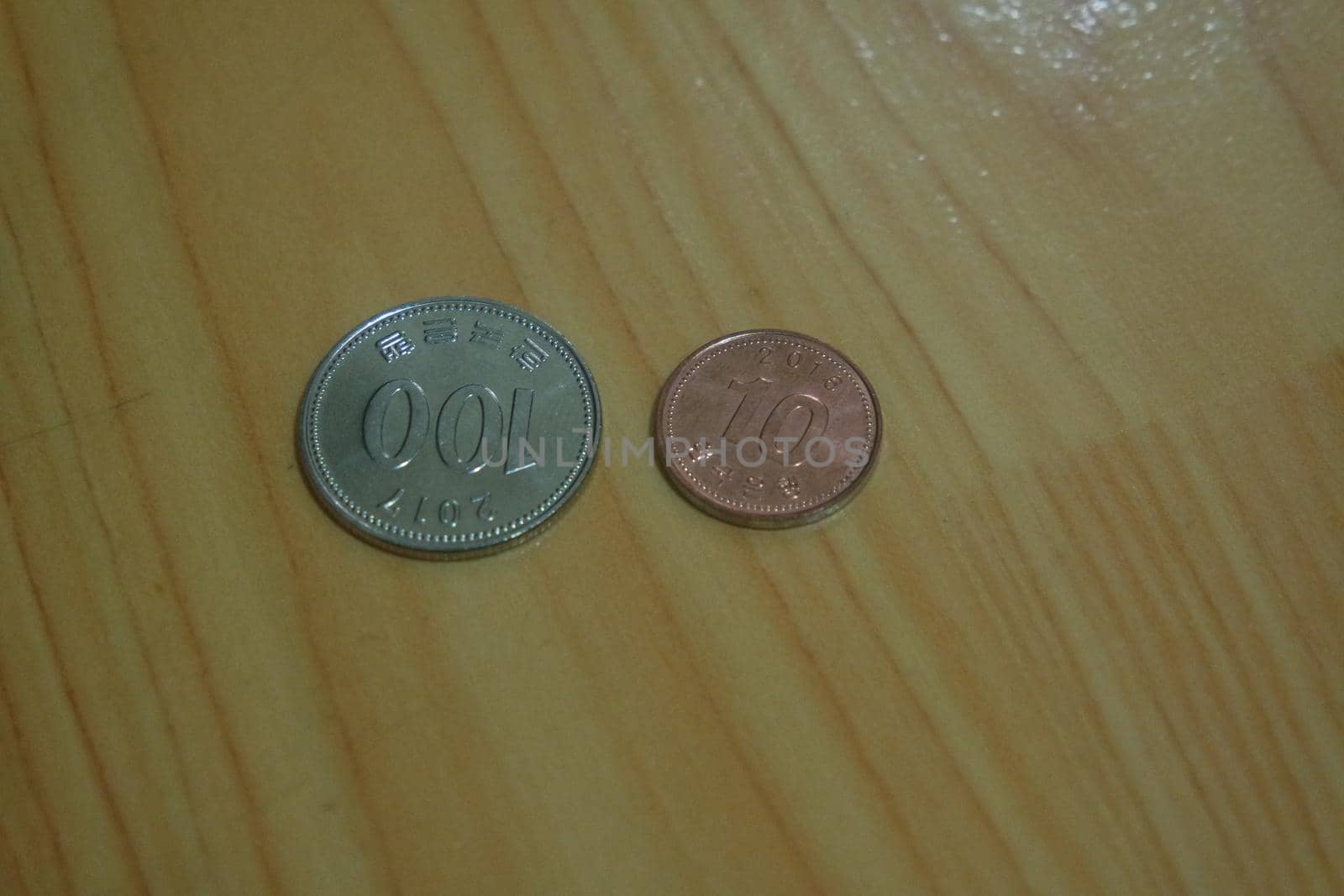 Korean won coin scattered over a wooden floor by Photochowk