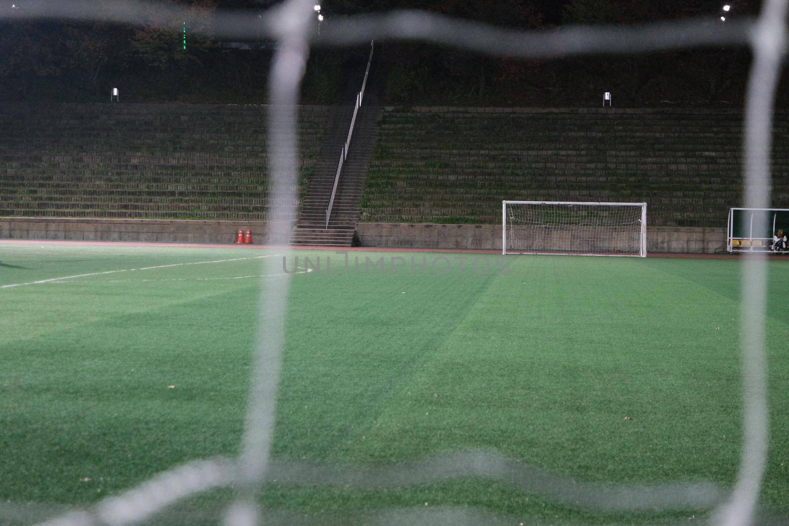 Night view of a soccer goal net under flood lights. Closeup view of goal net in a soccer playground