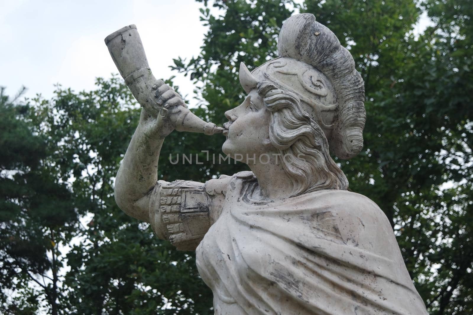 Stone sculpture of a Triton, blowing on his conch shell trumpet. by Photochowk