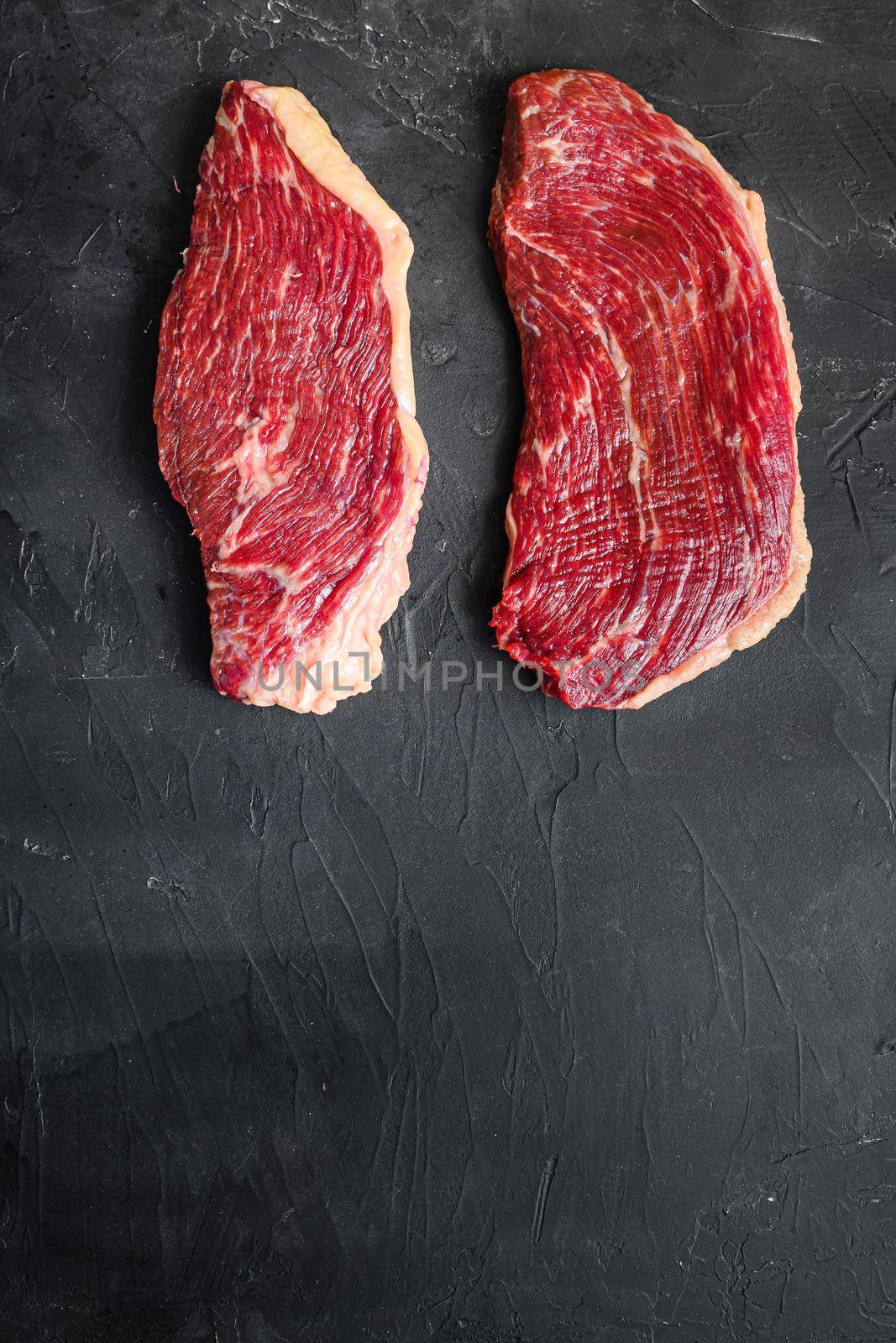 Picanha raw beef steaks, two cuts on black textured background, top view with space for text