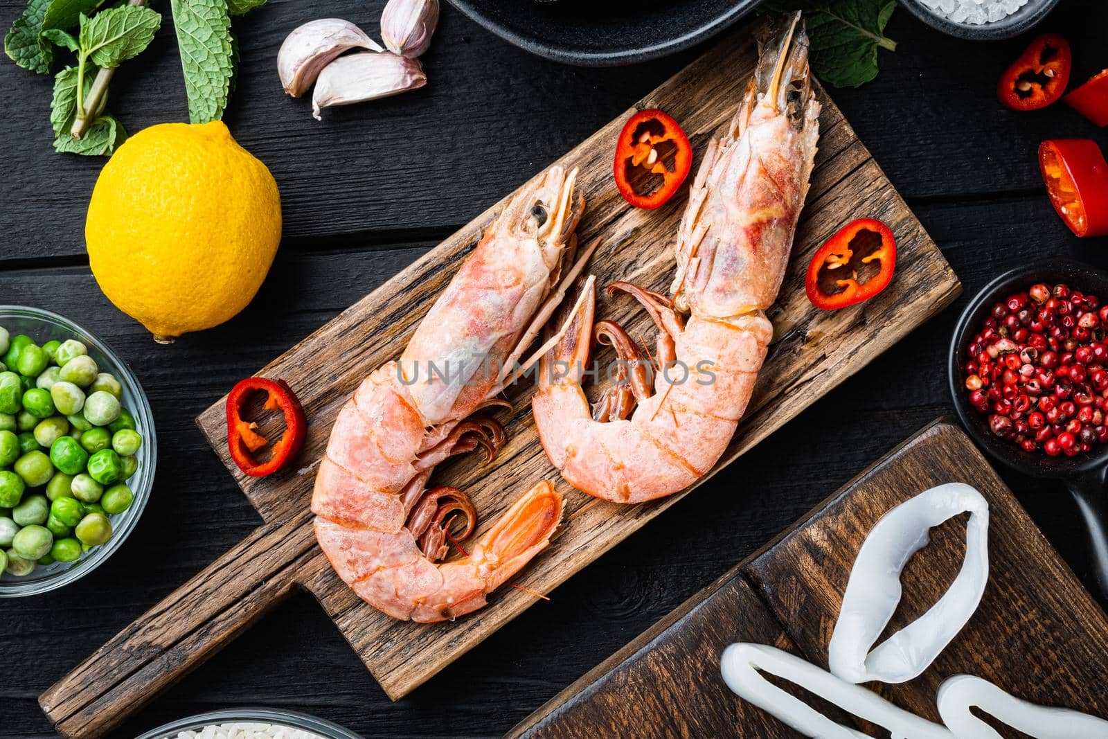 Seafood shrimps prawns on wooden board on black wooden background, flat lay, food photo.