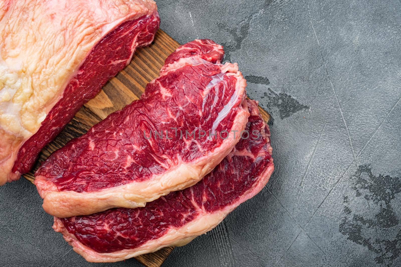 Raw ambassador beef steak cut, on gray background, top view, with copy space for text