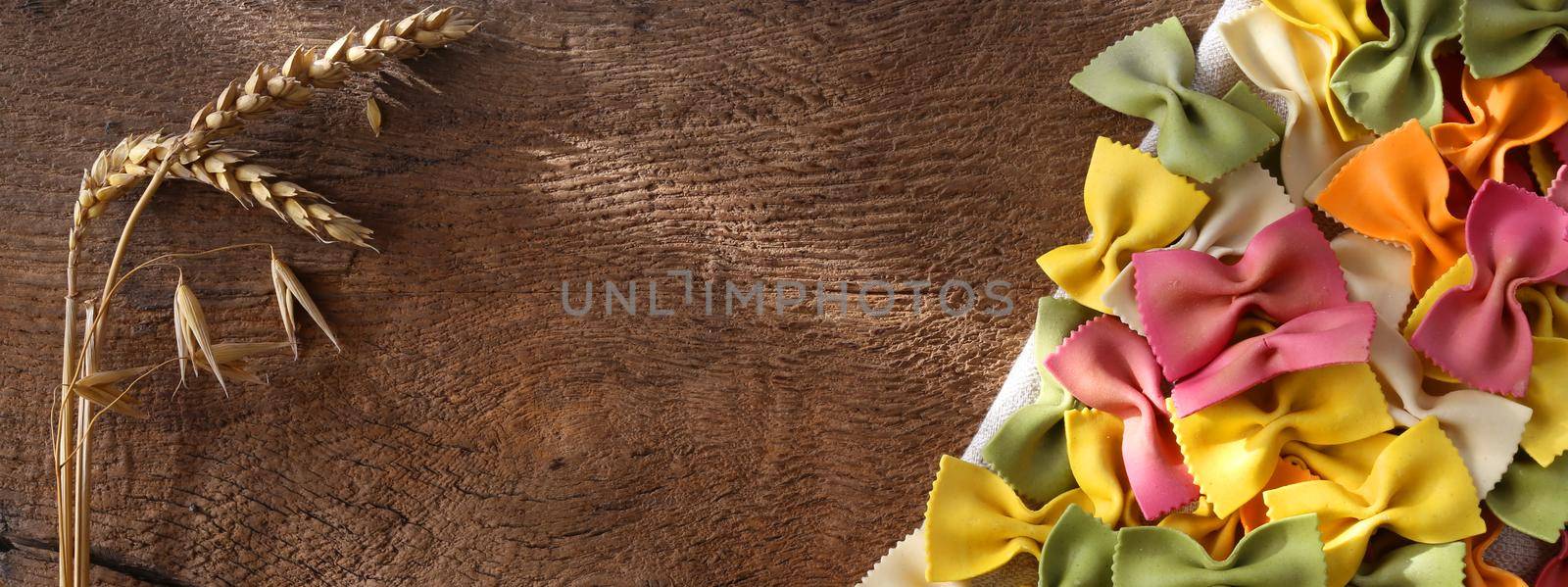 Italian pasta farfalle. Colourful pasta background with rye on old wooden rustic kitchen background. Pasta recipes concept. Horizontal flat lay. Place for text, copy space