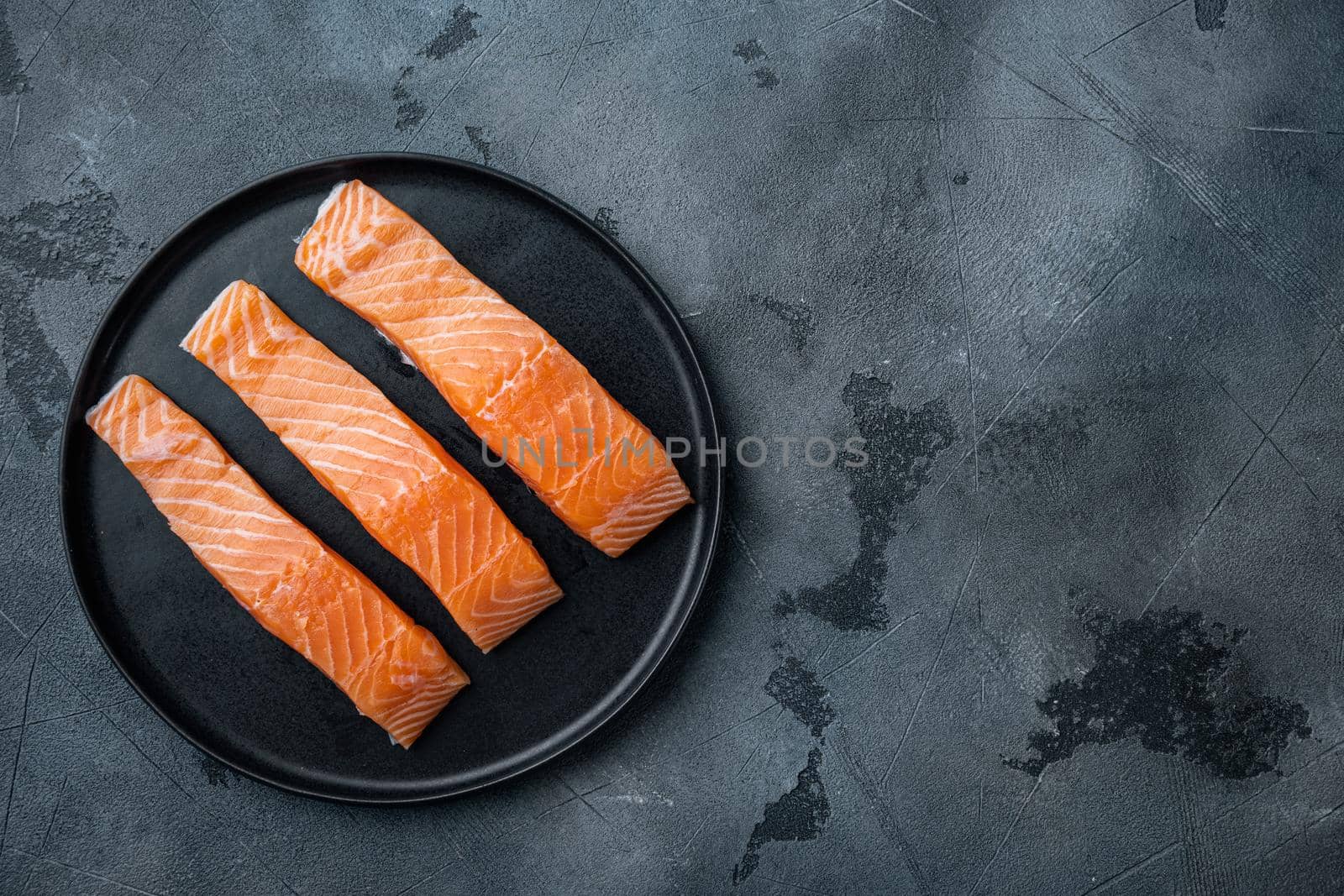 Fresh raw salmon fillet cuts, on grey background, flat lay with space for text