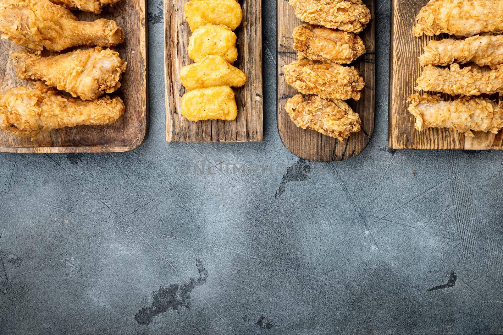 Homemade crispy fried chicken parts on grey background, top view, with copy space.