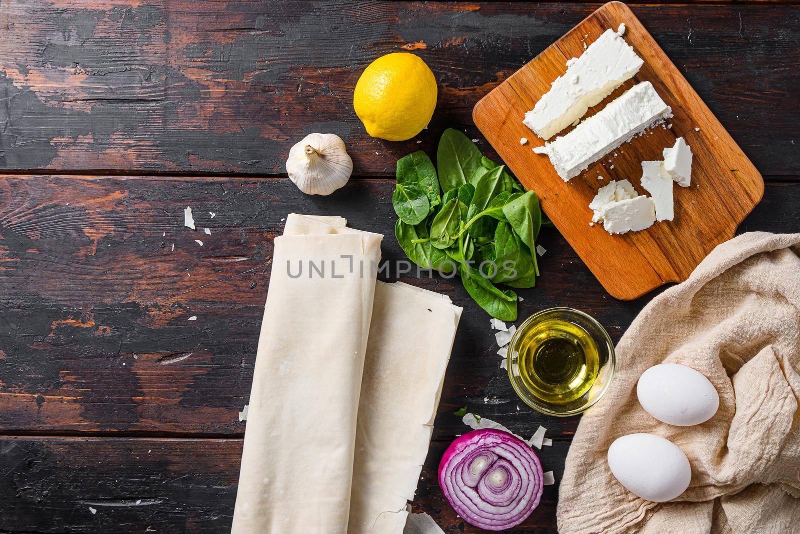 Greek spanakopita ingredients filo spinach eggs feta top view on dark wooden background space for text