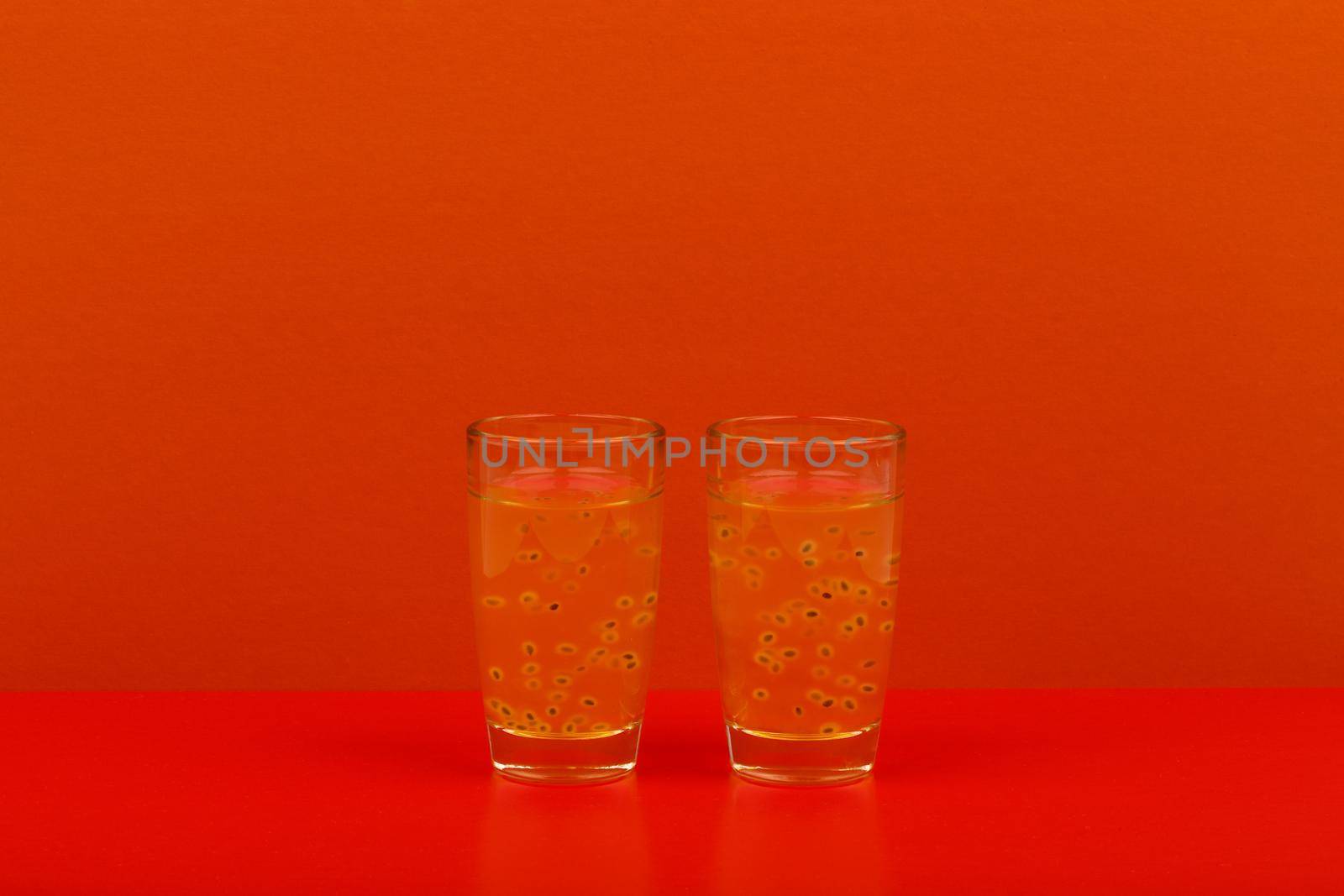 Minimalistic still life in vivid colors with two shots with fruit drink on red table against red background with copy space. 