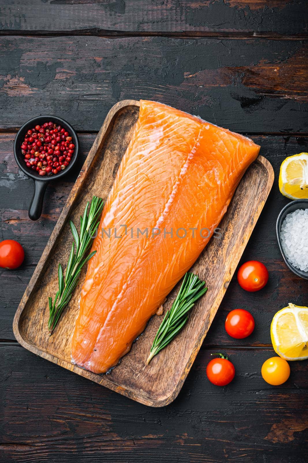 Fresh whole salmon fillet on wooden dark planks, flat lay.